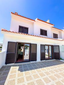 a white house with black shutters on it at Baleal Bay Guesthouse in Baleal