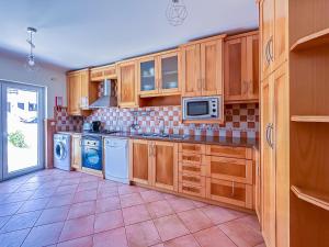 a kitchen with wooden cabinets and a tile floor at Baleal Bay Guesthouse in Baleal