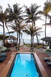 a swimming pool with palm trees and the ocean at Edelweiss Resort in Mirissa