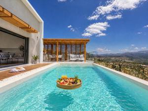 a pool with a bowl of fruit on the edge of a house at Villa Irene Tolo in Tolo