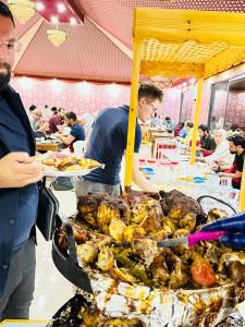 a man standing in front of a buffet of food at Wadi Rum Lana luxury camp in Wadi Rum