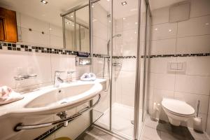 a bathroom with a shower and a sink and a toilet at Pension Berger in Oberlech