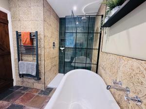 a bathroom with a tub and a glass shower at Vale View Cottages - The Stables in Prestatyn +17 photos