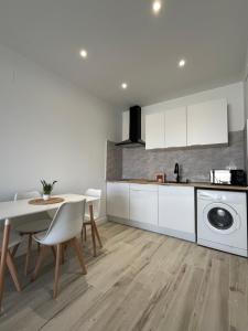 a kitchen with white cabinets and a table with chairs at El Rinconcito de la Jara con Parking para varios coches in Sanlúcar de Barrameda