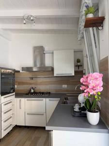 a kitchen with white cabinets and a sink and pink flowers at Beach house airport in Fiumicino +12 photos