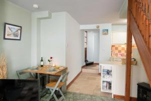 a dining room with a table and a kitchen at Motcombe Cottage in Hatherleigh