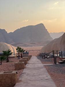 a path in the desert with a mountain in the background at Wadi Rum Lana luxury camp in Wadi Rum