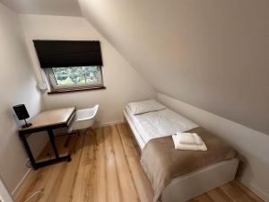 a small bedroom with a bed and a desk at Domek nad jeziorem Kamionki Małe in Kamionki Małe