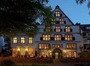 Un grand bâtiment blanc avec des fenêtres éclairées la nuit dans l'établissement Galerie Hotel, à Paderborn