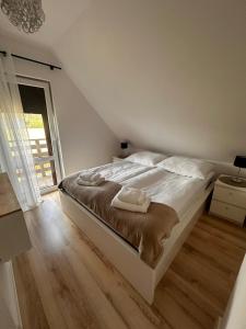 a white bed in a room with a wooden floor at Domek nad jeziorem Kamionki Małe in Kamionki Małe