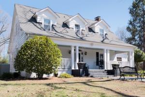 a white house with a bench in front of it at Swamp Rabbit Inn TR in Travelers Rest