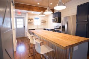 a kitchen with a wooden counter and white chairs at Swamp Rabbit Inn TR in Travelers Rest
