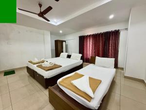 a bedroom with two beds and a ceiling fan at Hotel Sai in Udupi