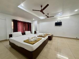 a bedroom with a large bed with a ceiling fan at Hotel Sai in Udupi