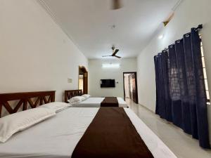 two beds in a bedroom with a ceiling fan at Nanasu Home stay in Malpe