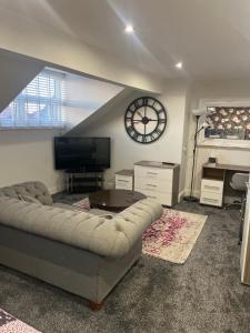 a living room with a couch and a clock on the wall at Fox lodge in Blackpool