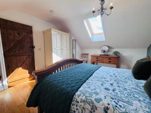 a bedroom with a bed with a blue comforter at Vale View Cottages - The Stables in Prestatyn