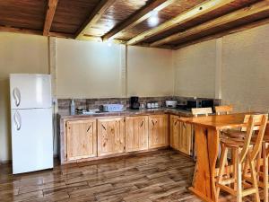 a kitchen with a white refrigerator and a wooden table at Poas Green Chalets in Fraijanes