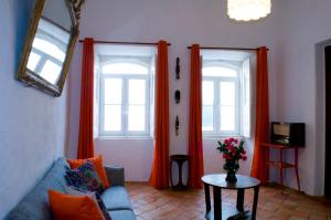 uma sala de estar com cortinas cor de laranja e um sofá azul em Casa da Avó Nina em Fuzeta