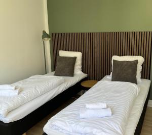 two beds in a hotel room with towels on them at Hotel Færgelunden in Jægerspris +6 photos