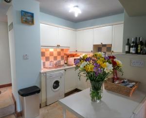 a kitchen with a vase of flowers on a table at Motcombe Cottage in Hatherleigh +14 photos