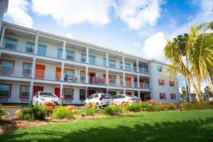 a large white building with cars parked in front of it at The Sunshine Hotel and Suites in George Town