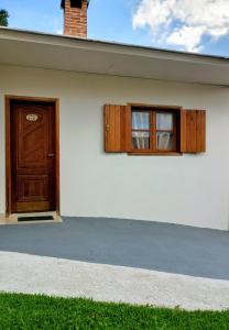 a white house with a door and two windows at Chalés e suítes lima in Monte Verde +138 photos