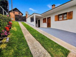 a house with a grass yard and a driveway at Chalés e suítes lima in Monte Verde