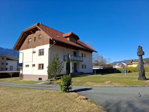 a white house with a wooden roof on a street at FEWO Erika in Presseggen