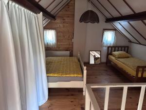 two beds in a room with wooden floors at Authentic Dikehouse at sea in Walsoorden