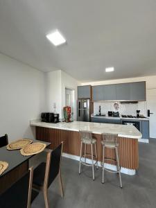 a kitchen with a counter and two tables and chairs at Apê completo 2 quartos 300m da praia15min Beto Carreiro in Piçarras