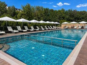 a large swimming pool with chairs and umbrellas at Hotel Magnific in Kranevo
