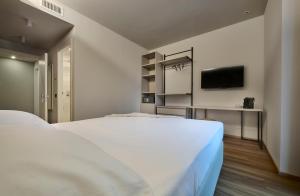 a bedroom with a large white bed and a tv at Monolocale 1 - via Sassi, Lecco in Lecco