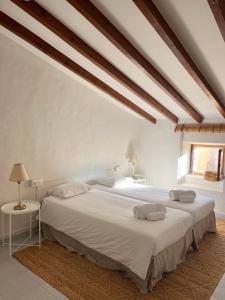 a white bedroom with a large bed with two pillows at Ca'n Ruquet in Campanet