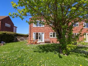 a brick house with a tree in the yard at Seashells at Runswick Lodge in Saltburn-by-the-Sea