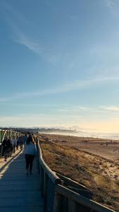 a group of people walking down a boardwalk on the beach at Charmant studio climatisé à deux pas de la plage! in Anglet +2 photos