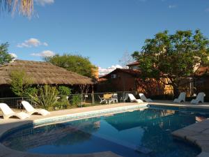 a swimming pool with lounge chairs and a house at Cabañas Yunyay in Villa Cura Brochero