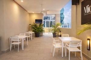 a dining room with tables and chairs and a window at Hotel Mio Panamá in Panama City