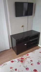 a black dresser with a flat screen tv on a wall at Pousada Cantinho da Idná in Uberlândia