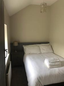 a bedroom with a white bed and a lamp at 2, The Lodge, Tideswell in Tideswell