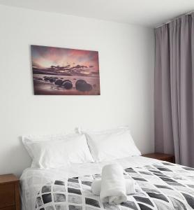 a bedroom with a white bed with a picture on the wall at Home Inn Timaru in Timaru