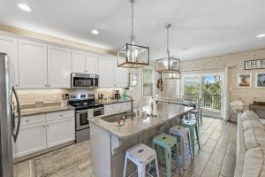 a kitchen with white cabinets and a kitchen island with stools at PRIME Coral Dreams Walk to Beach Pool Pets Near The Hangout Parking in Gulf Shores