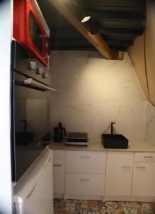 a small kitchen with white cabinets and a red appliance at Nuit Insolite dôme Reinette tout confort in Châtenois