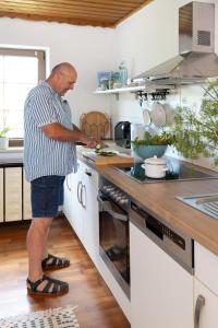 a man standing in a kitchen preparing food at Ferienhaus-Weinmeyer in Paasdorf