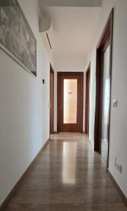 an empty hallway with white walls and wooden doors at CMBYN Stanza in Casa Condivisa e Bici Gratis in Crema