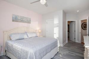 a white bedroom with a bed and a ceiling fan at Salty Girl by Oak Island Accommodations in Oak Island