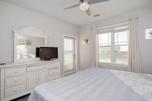 a white bedroom with a bed and a tv at Salty Girl by Oak Island Accommodations in Oak Island