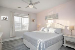 a white bedroom with a bed and a window at Salty Girl by Oak Island Accommodations in Oak Island