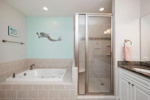 a bathroom with a bath tub and a shower at Salty Girl by Oak Island Accommodations in Oak Island +32 photos