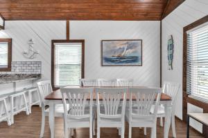 a dining room with a table and white chairs at Salty Dawg by Oak Island Accommodations in Oak Island